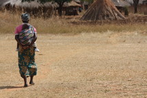 Woman carrying baby through field
