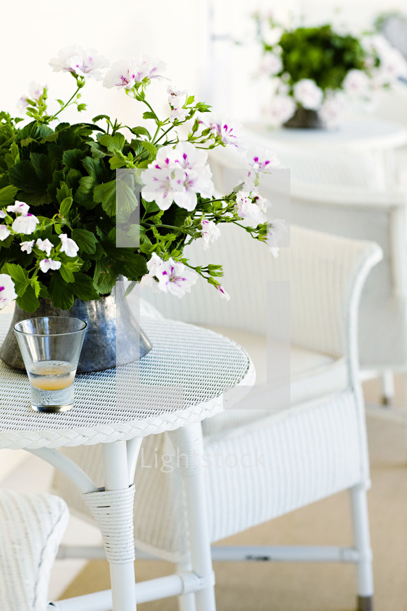 White wicker table chair with geranium centerpieces outdoor porch patio
