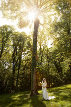 Bride standing in a forest holding flowers