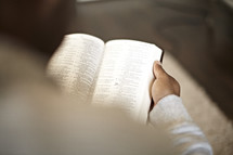 An over-the-shoulder view of a man reading the bible