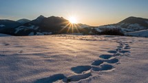 Winter sunset in frozen snowy alpine landscape in beautiful sunny evening nature with footprints in the snow time-lapse
