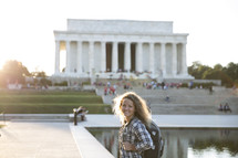 a girl with a back pack standing in front of the Lincoln Memorial.