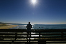a man standing on a pier looking at his phone 
