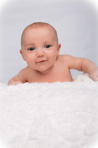 A baby crawling on a white blanket 