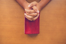 praying hands over a bible 