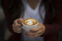 a young woman holding a cup of coffee with creamer 