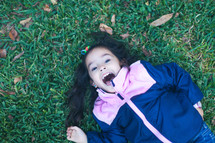 a little girl rolling in the grass 