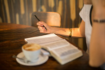 a woman reading a Bible at a Bible with a cappuccino 