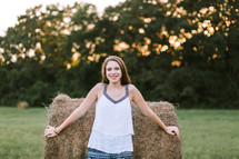 teen girl leaning against a hay bale 