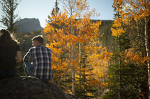 man and woman sitting on a rock in a fall forest 