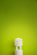 An energy efficient light bulb on a green background.