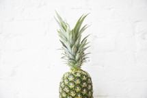 pineapple fruit against a white brick wall 