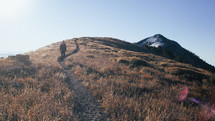 a man walking on a path on a mountaintop 