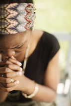African-American teen sitting outside on a porch swing praying.