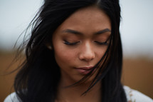 face of a young woman with closed eyes praying 