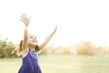 toddler standing outdoors with raised hands 