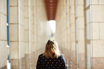 a woman looking down a corridor 