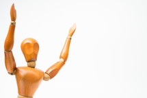 wooden mannequin with raised hands 