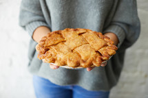 a woman holding a homemade pie 