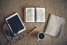 headphones, tablet, open Bible, pen, journal, and coffee cup 