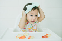 toddler girl eating in a highchair 