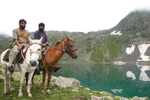 men on horseback next to a lake 