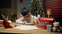 Kid writing Christmas letter on his notebook 