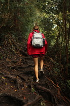 a woman hiking up a trail covered by tree roots in Hawaii 