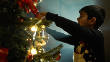 Kid preparing tree for Christmas with decorations