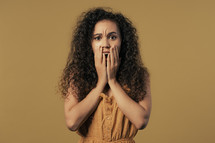 Woman afraid of something, she in shock on yellow backdrop.Holding head, screaming. High quality photo