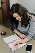 a businesswoman sitting at a desk writing notes in a notebook 