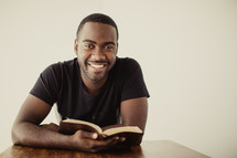 man reading a Bible and smiling 