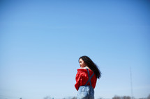 portrait of a woman standing outdoors against a blue sky 