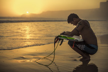 squatting surfer in meditation and prayer at sunrise
