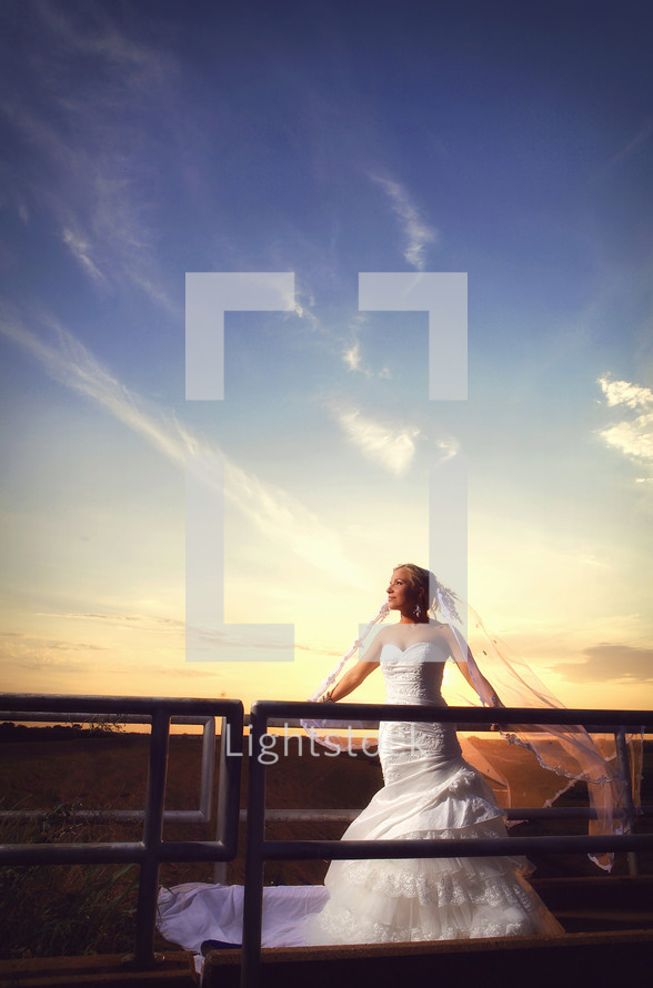 bride standing on bridge against sunset