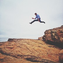Man jumping from rock in midair
