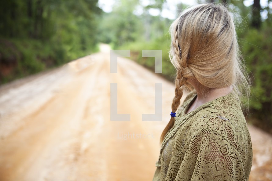 Woman looking at open dirt road 