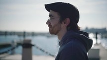 A contemplative young man walks along the docks in the city