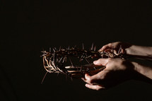 hands holding out a crown of thorns 