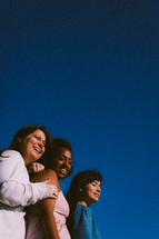 three female friends under a blue sky 
