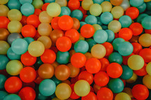 Multi-colored plastic balls in children's attraction. Funny pool, top view. Entertainment for kids. Wallpaper, texture, pattern.
