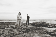 a young family standing on a rocky beach 