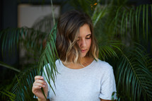 a woman standing in palm fronds 