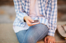 a woman sitting on a stone bench checking cellphone 