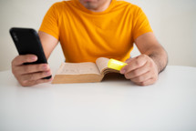 a man reading a Bible and looking at a cellphone app 