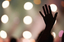 silhouette of a raised hand at a concert 
