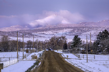 A Dirt Urban Road leading to a Snow Capped Longs Peak Mountain after a fresh snow fall