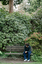 a woman praying sitting on a park bench 
