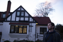 a man standing outdoors in front of a house 