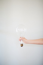 a woman holding a large lightbulb 